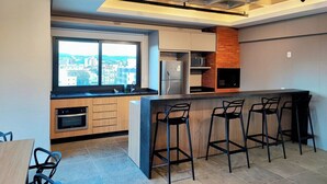 Ett modernt kök med ett stort fönster, en inbyggd ugn och en bardisk med barstolar.