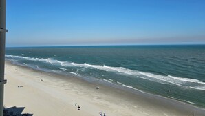 A beach with waves, people, and a clear sky.