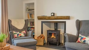 A cozy living room with a fireplace, a bookshelf, and two armchairs. - Stunning Sea Views in Central Burntisland (Burntisland)