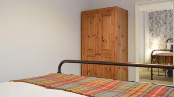 A bedroom with a bed, a wooden wardrobe, and a door leading to another room. - Stunning Sea Views in Central Burntisland (Burntisland)