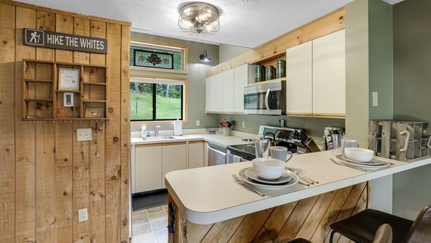 A modern kitchen with wooden accents, a central island, and a sign reading "HIKE THE WHITES". - New Hampshire vacation getaway with gorgeous mountain views—ski, hike, swim! (Thorton)