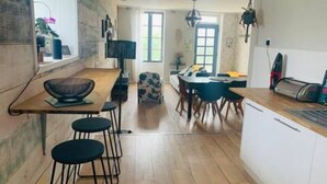 Une cuisine moderne avec un plancher en bois, un coin repas comprenant une table et des chaises, et une fenêtre laissant entrer la lumière naturelle.