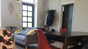Un coin repas avec une table et des chaises en bois, un canapé et un mur décoré de motifs.