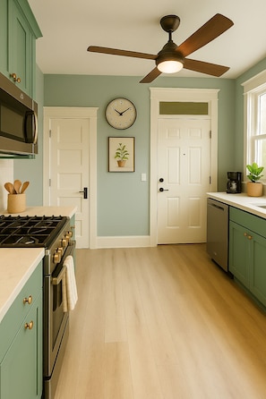 A kitchen with a stove, oven, microwave, ceiling fan, and a clock on the wall.