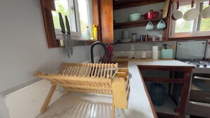 Une cuisine équipée d’un égouttoir en bois, d’un évier et de divers ustensiles de cuisine.