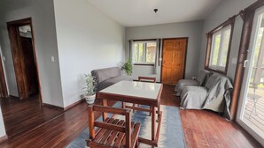 Un vaste espace de vie comprenant une table à manger en bois, un canapé et une plante en pot.