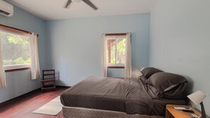 A bedroom with a bed, a nightstand, a lamp, and a chair. - House On The Hill majestic ocean view walking distance to beach and restaurants (Roatan)