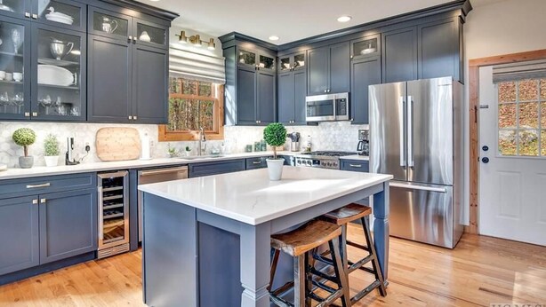 A modern kitchen with dark cabinets, stainless steel appliances, and a large island with stools. - Fern Cliff - A cozy retreat in Cashiers (Cashiers)