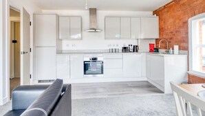 Una cocina moderna con armarios blancos, horno empotrado y pared de ladrillo.
