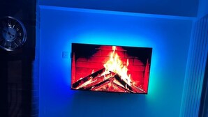 Una sala de estar con televisor de pantalla plana, chimenea y sofá moderno.