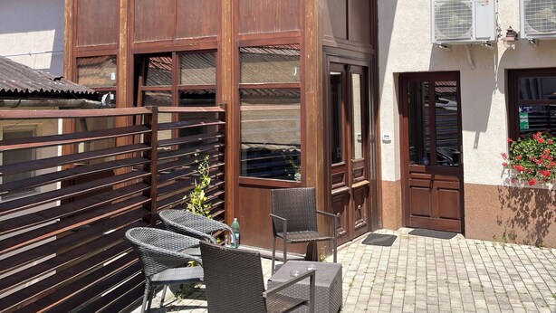 A two-story building with a balcony, a wooden fence, and outdoor furniture. - Cozy Apartment (Brasov)