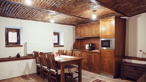 A kitchen with wooden cabinets, a microwave, and a dining table with chairs. - Cozy Apartment (Brasov)