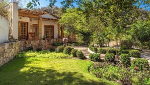 A house with a stone facade, wooden porch, and a well-maintained garden with various plants and a pathway leading to the entrance. -  La Dulce Vista Hotel & Villas - Sierra Madre Puerto Vallarta (Puerto Vallarta)