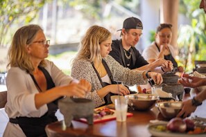 A group of people engaged in a cooking activity using traditional stone tools.