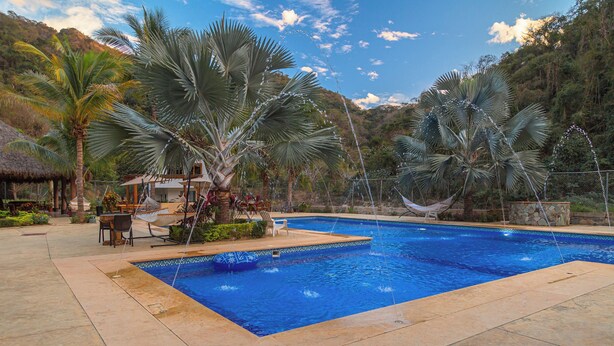 A swimming pool with a thatched-roof structure, palm trees, and a hammock. -  La Dulce Vista Hotel & Villas - Sierra Madre Puerto Vallarta (Puerto Vallarta)