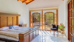 A bedroom with a large bed, wooden headboard, and a view through a glass door to an outdoor area. -  La Dulce Vista Hotel & Villas - Sierra Madre Puerto Vallarta (Puerto Vallarta)