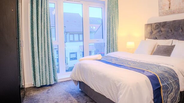 Ein Schlafzimmer mit Bett, Vorhängen, einem Fenster und einem Bild an der Wand.