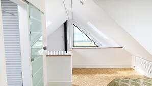 A modern room with a sloped ceiling, a skylight, and a view of the outdoors. - Luxurious Designer Penthouse - Grand Bay Views (Poole)