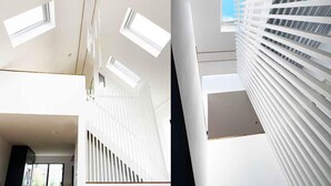 A modern interior with a high ceiling, skylights, and a staircase with white railings. - Luxurious Designer Penthouse - Grand Bay Views (Poole)
