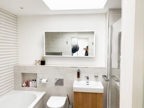 A modern bathroom with a bathtub, toilet, and sink. - Luxurious Designer Penthouse - Grand Bay Views (Poole)
