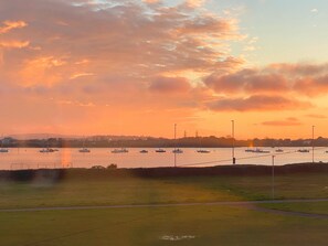 A marina with boats docked, a grassy area in the foreground, and a sunset sky. - Luxurious Designer Penthouse - Grand Bay Views (Poole)