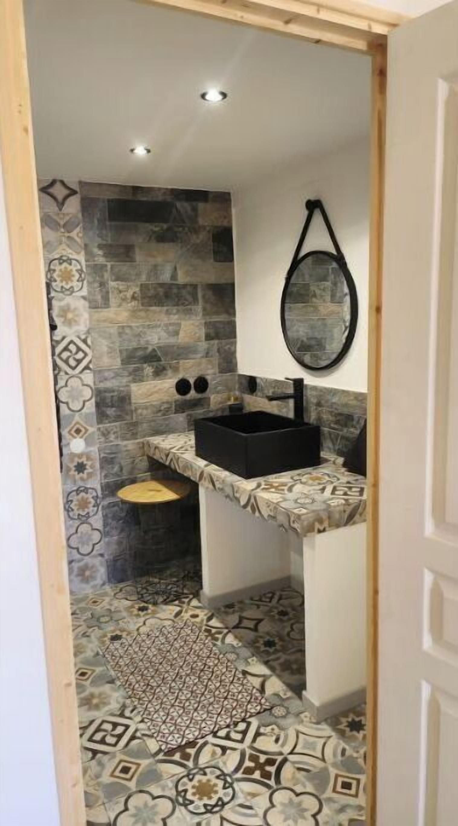 A bathroom with a black sink, patterned tiles, and a mirror.