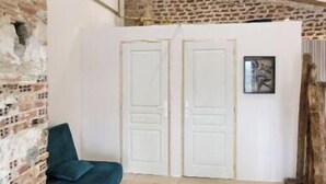 A room with a stone wall, a blue sofa, and a white door. - Location Petit Loft Dans Vaste Domaine (Esparron)
