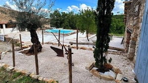 A courtyard with a swimming pool, olive trees, and a stone wall. - Location Petit Loft Dans Vaste Domaine (Esparron)