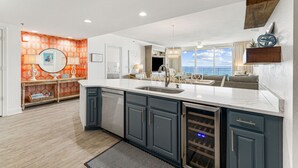 A modern kitchen with a large island, built-in appliances, and a view of the ocean. - WaveSong: Luxurious Beachfront Condo at Navarre Beach. Sleeps 9 (Navarre)