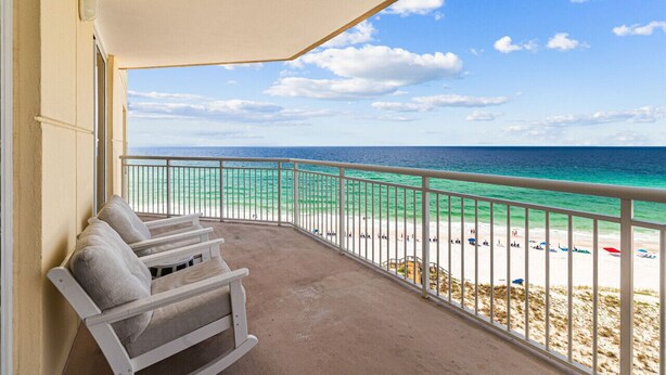 A balcony with white cushioned chairs, a view of a beach with clear turquoise water, and a white railing. - WaveSong: Luxurious Beachfront Condo at Navarre Beach. Sleeps 9 (Navarre)