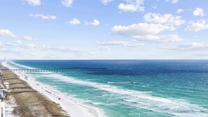A coastal beach with a pier extending into the ocean, sandy shore, and clear skies. - WaveSong: Luxurious Beachfront Condo at Navarre Beach. Sleeps 9 (Navarre)
