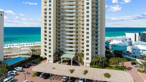 A high-rise hotel with multiple balconies, a swimming pool, and a beach view. - WaveSong: Luxurious Beachfront Condo at Navarre Beach. Sleeps 9 (Navarre)