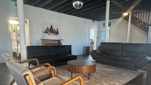 Ett modernt vardagsrum med en svart soffa, ett soffbord i trä och en beige fåtölj.