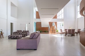 A spacious lobby with a modern staircase, a seating area with patterned sofas, and a dining setup. - Mansao 6 suites c piscina e jacuzzi 082M (Ipojuca)