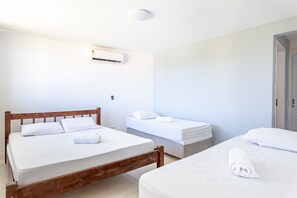 A hotel room with two beds, a ceiling-mounted air conditioner, and a door to the right. - Mansao 6 suites c piscina e jacuzzi 082M (Ipojuca)