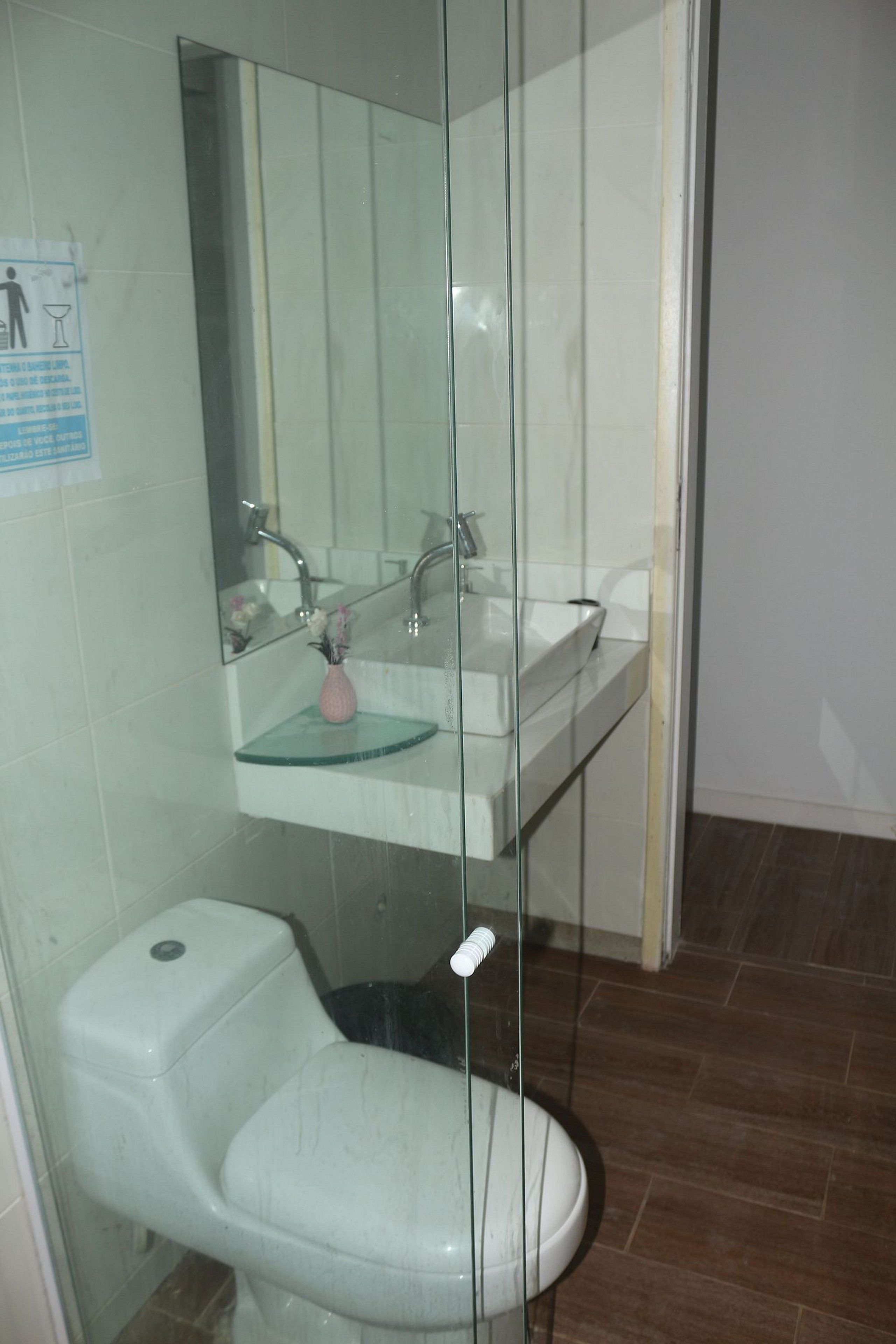 Un baño con ducha de vidrio, lavamanos blanco y un inodoro.