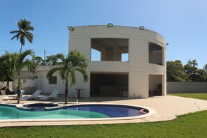 Una casa moderna con piscina, un porche cubierto y un garaje.
