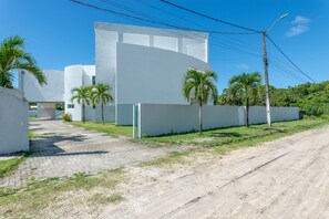 Un edificio moderno con fachada blanca, un camino pavimentado y palmeras.