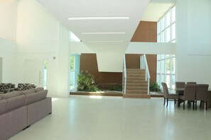 A spacious living area with a sofa, dining table, chairs, and a staircase leading to an upper level. - Mansao 6 suites c piscina e jacuzzi 082M (Ipojuca)