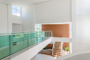 Ein modernes Interieur mit Glastrennwand, Holztreppe und Wandverkleidung mit Muster.