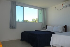 Una habitación con dos camas, una ventana con cortinas, un aire acondicionado de pared y una pared blanca lisa.