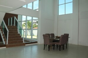 A spacious room with a modern staircase, large windows, and a dining area with chairs and a table. - Mansao 6 suites c piscina e jacuzzi 082M (Ipojuca)