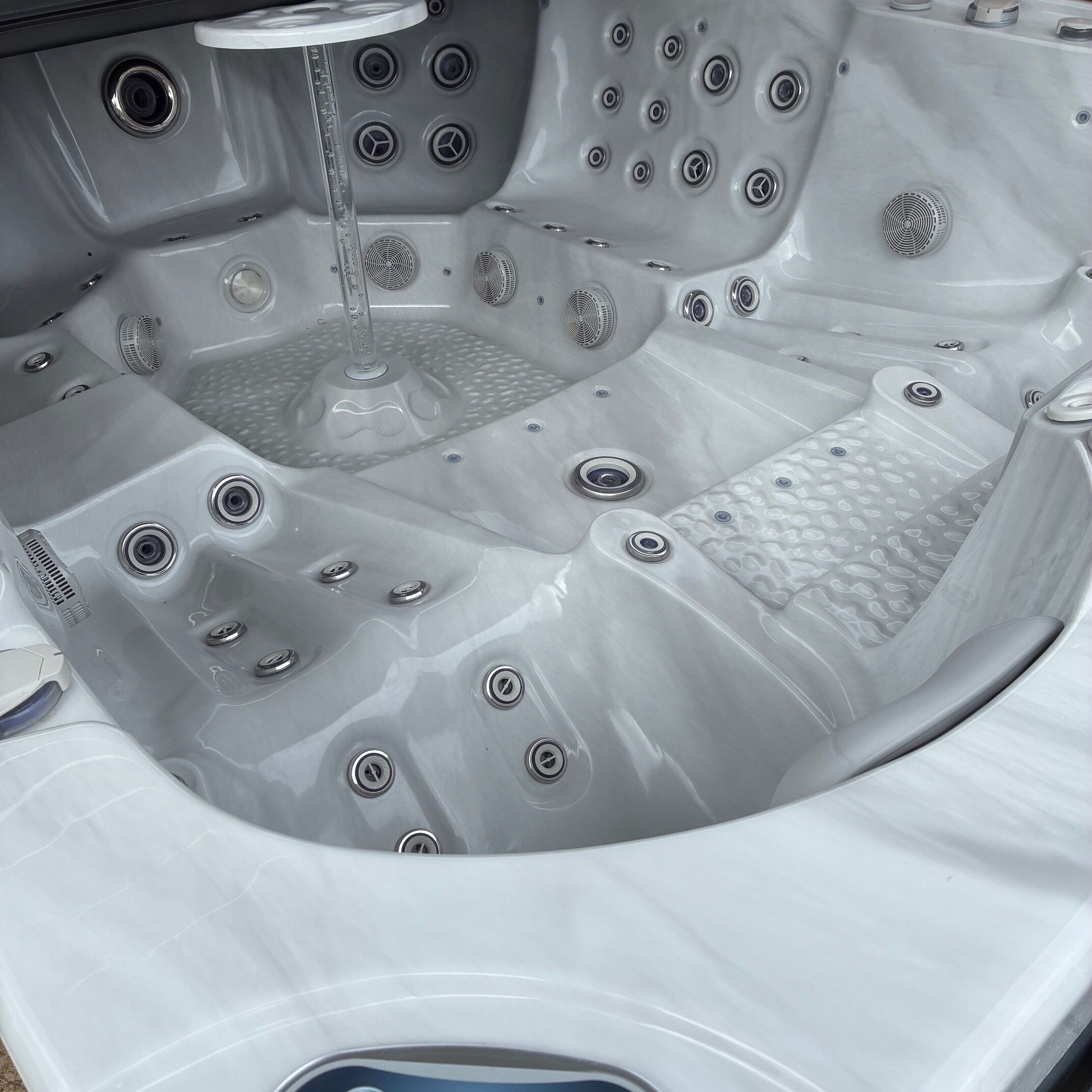 A hot tub with multiple seating areas, built-in jets, and a control panel.