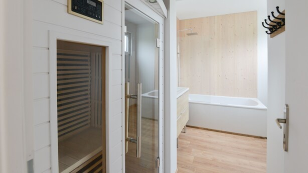 Un baño moderno con cabina de ducha de vidrio, tocador de madera y bañera.