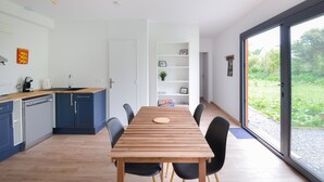 Una cocina moderna con una mesa de madera, sillas negras y vistas al exterior con vegetación.