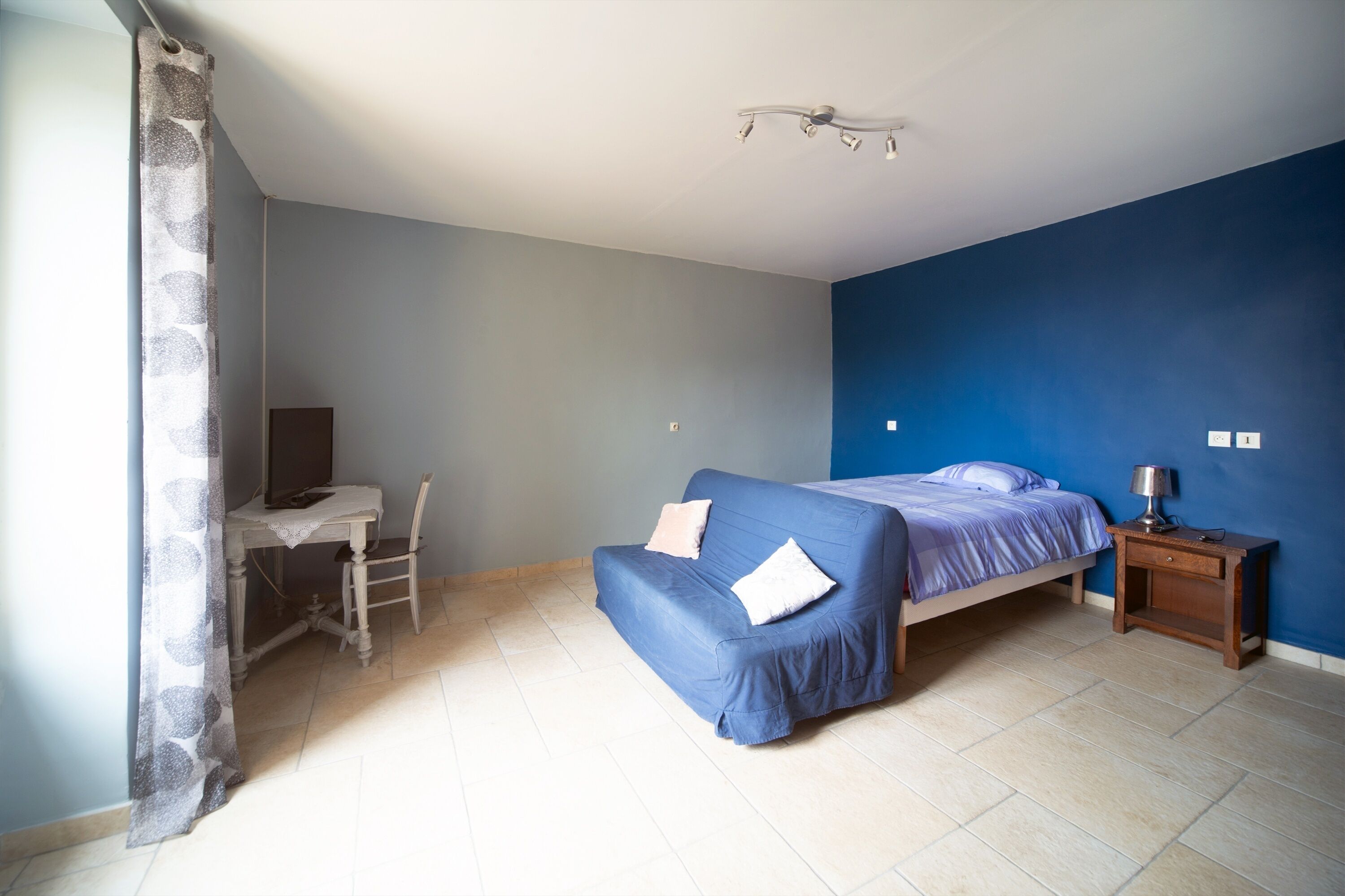 A bedroom with a bed, a desk, and a chair.