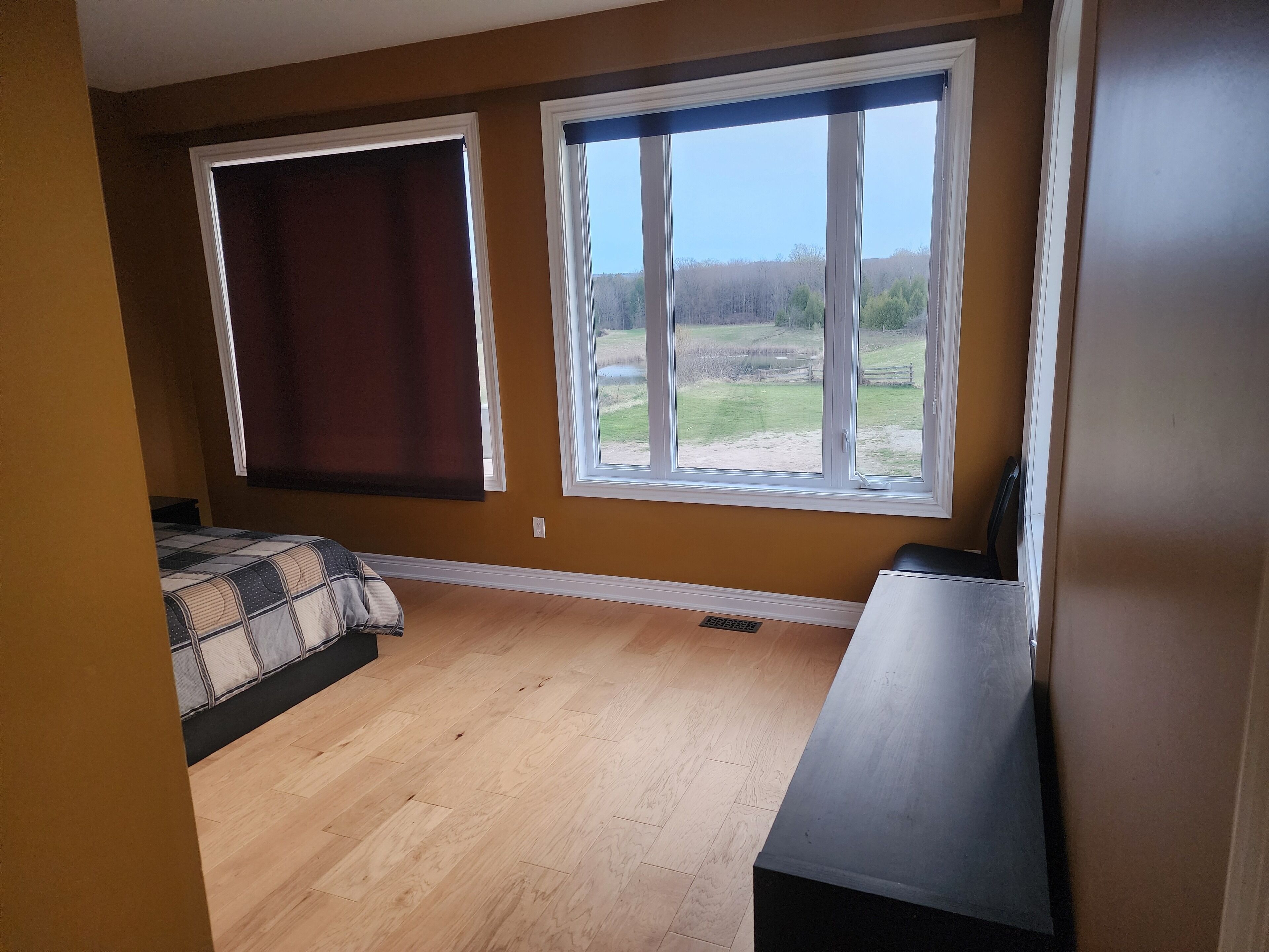Ein Zimmer mit zwei Fenstern, einem Bett und einem Schreibtisch.
