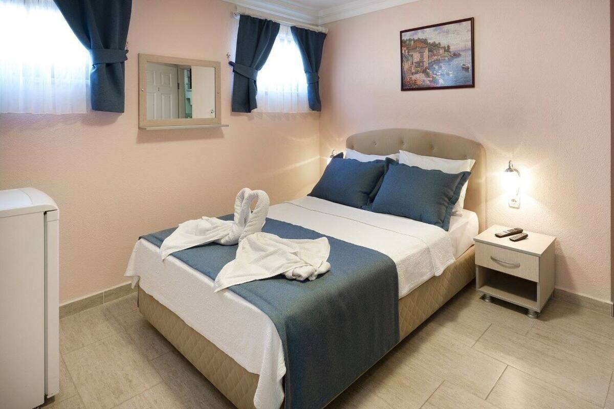 A neatly made bed with a blue and white bedspread, a bedside table with a lamp, and a small nightstand.