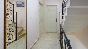 A narrow hallway with a white door, a staircase with black railings, and a small picture on the wall. - Begonvil Hotel Bozcaada (Bozcaada)
