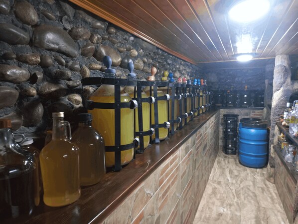 Zona de bar amb parets de pedra, prestatgeries de fusta i diversos recipients i amples.
